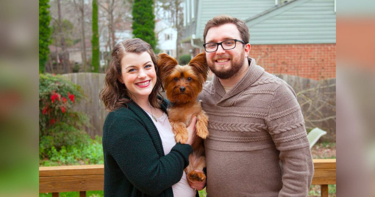 Sarah and Patrick smile with their dog, Oswald