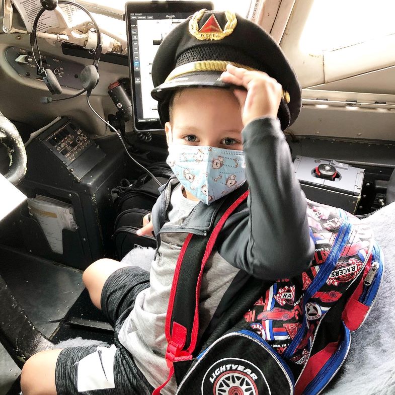 Hudson wearing mask sitting in cockpit of airplane.