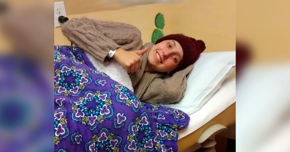 Greta laying in hospital bed with blanket and hat