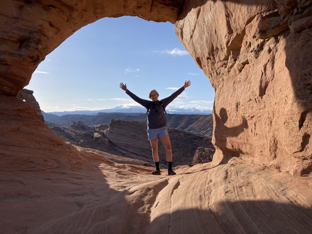 Martha on a hike in Moab, Utah, with her arms stretched above her head