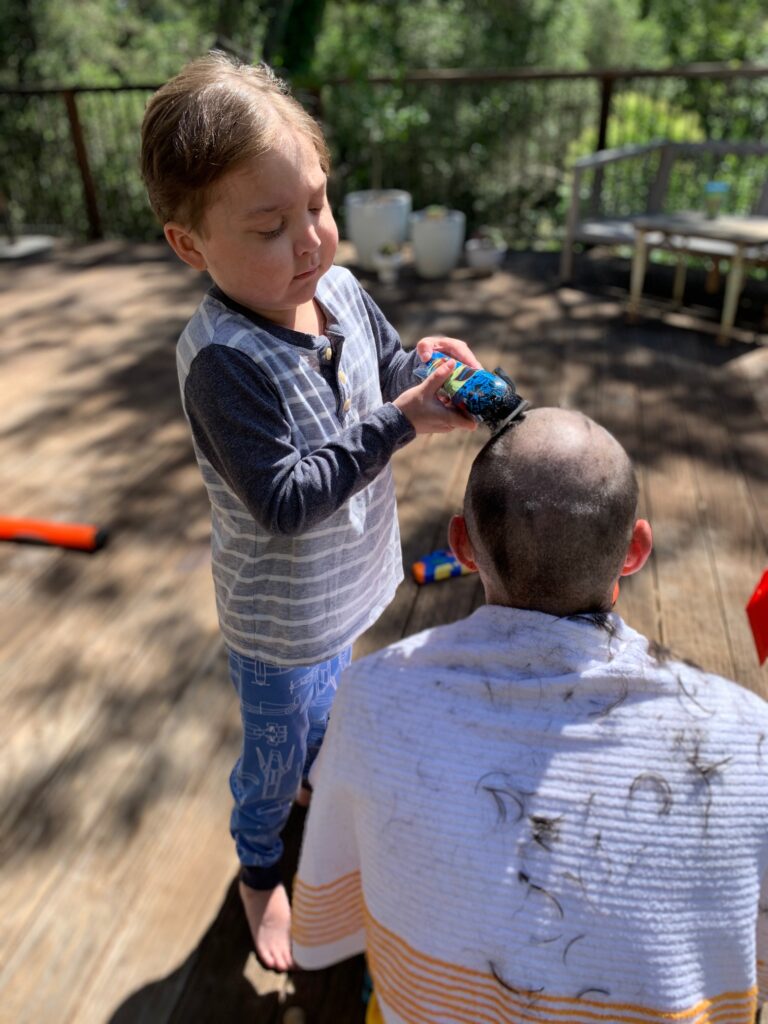 Camden shaving his dad's head in the backyard.