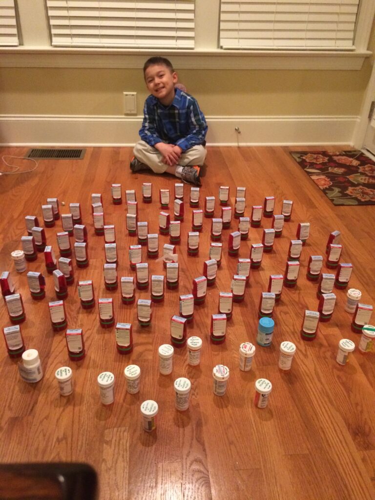 cancer survivor Scott surrounded by the pill bottles he's gone through during treatment
