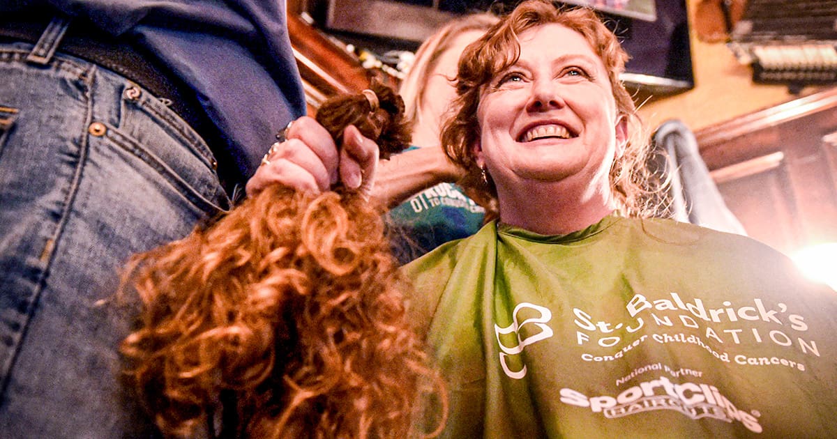 Adult woman proudly holding her red hair that was cut for a hair donation