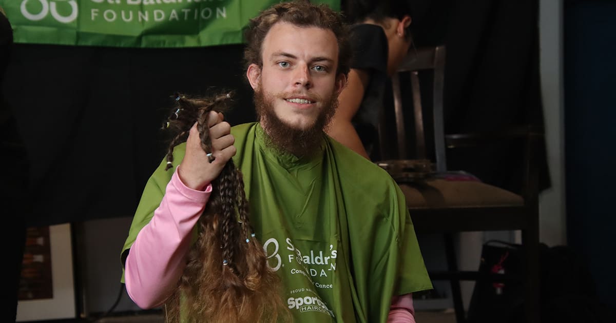 Smiling young man proudly holding braided hair donations