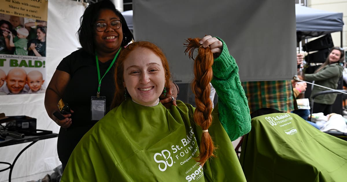 Young Trimee holding recently cut hair at a St. Baldrick's event