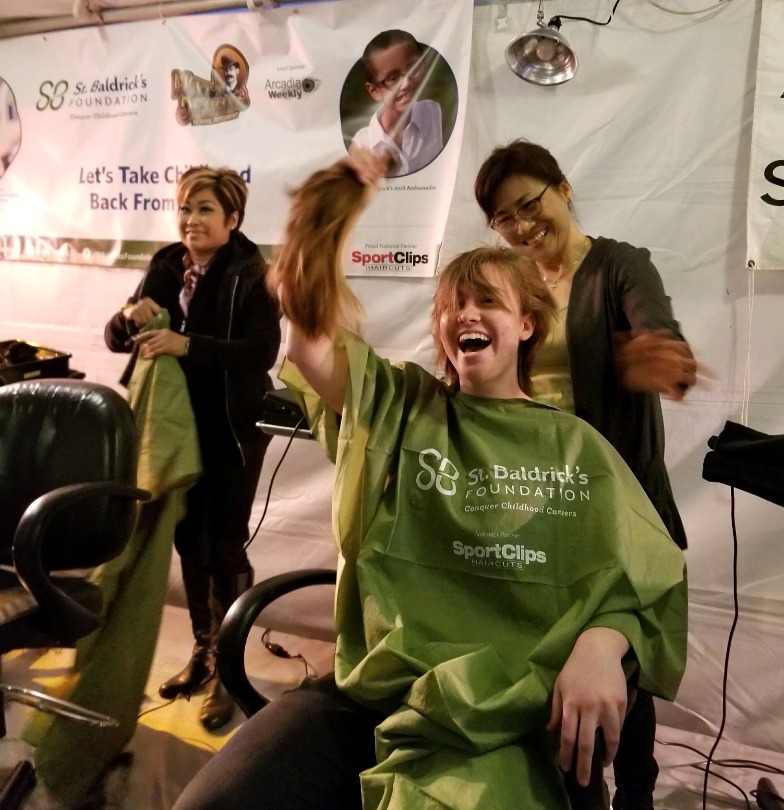 Female shavee grins during her shave in 2018 at the Matt Denny’s Ale House Event