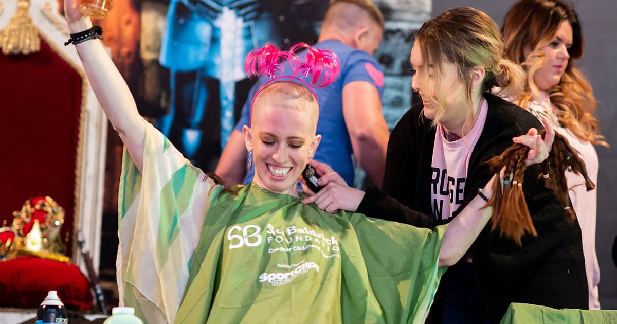 Adult woman holding her read hair for donations after being shaved