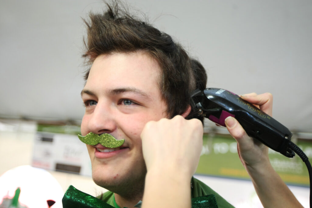 male shavee with a fake green mustache, ready to shave off his hair