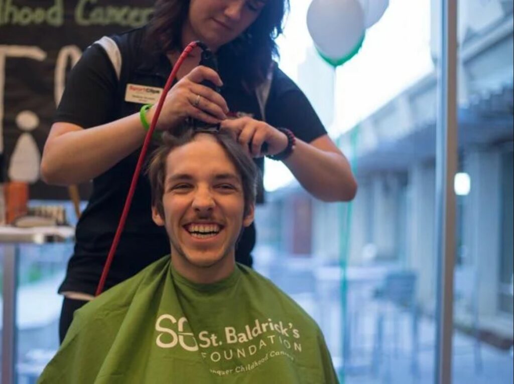 a male shavee sitting a barber chair, getting his head shaved