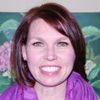A woman with vibrant red hair and a stylish purple scarf, looking confidently at the camera.