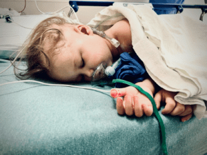 A little girl on a hospital bed with an oxygen mask