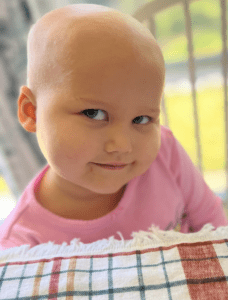 A little girl in in a pink shirt smiling