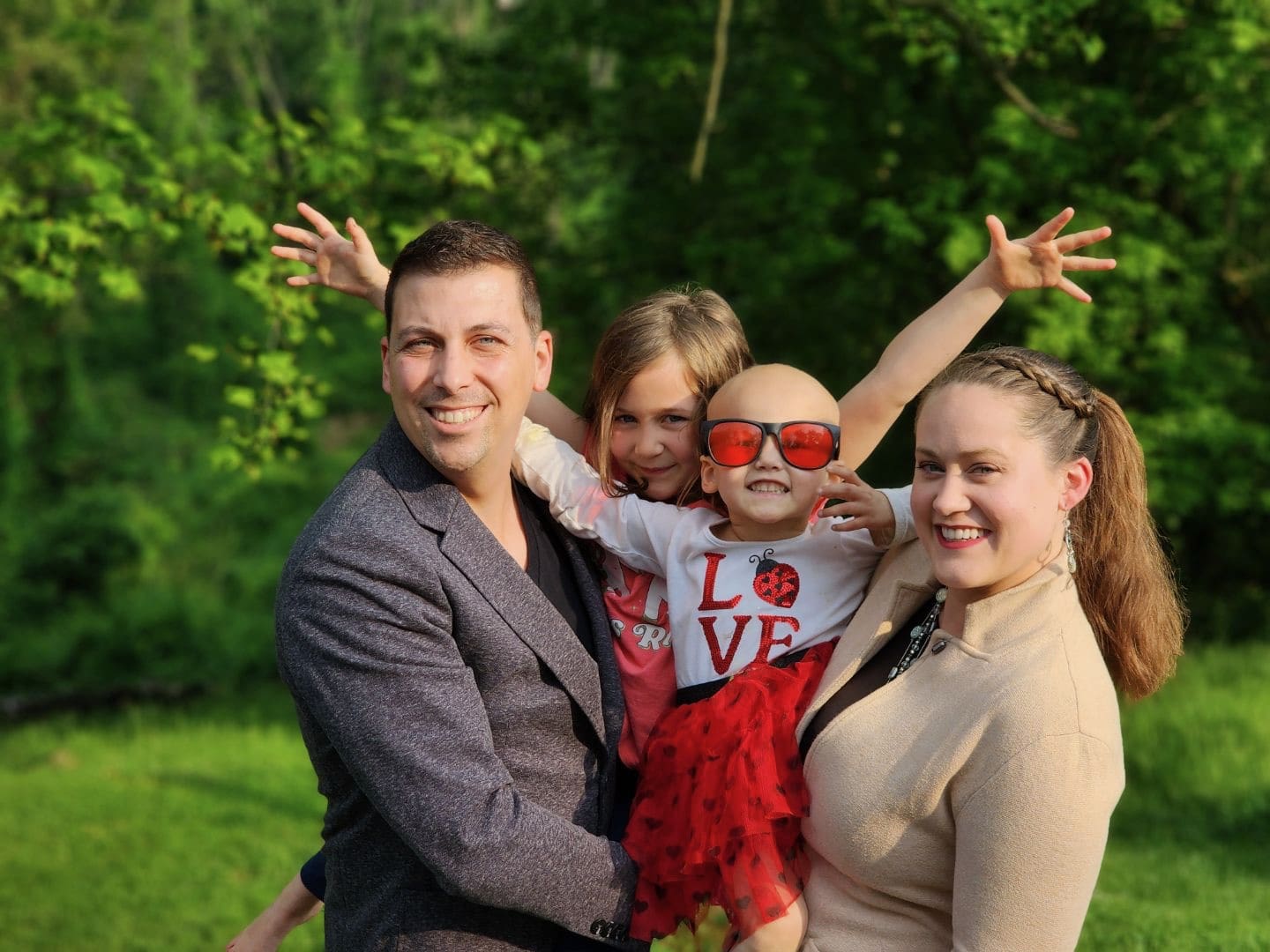 A family of 4 posing in a garden