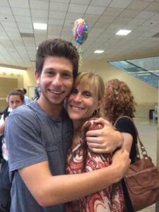A joyful reunion as a man and woman hug tightly in a public indoor space.