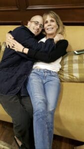 A man and woman embrace while sitting together on a couch, conveying warmth and affection.