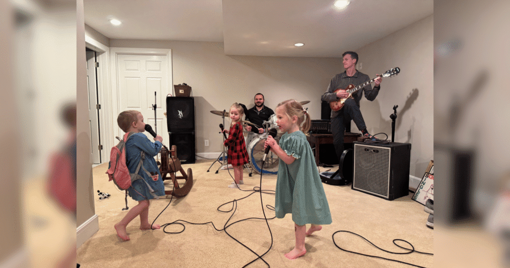 A group of children and adults joyfully playing various musical instruments in a bright, colorful room.
