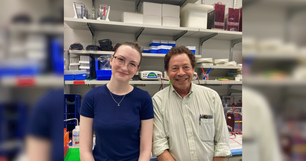 A man and woman stand in a laboratory surrounded by shelves filled with scientific equipment and materials.
