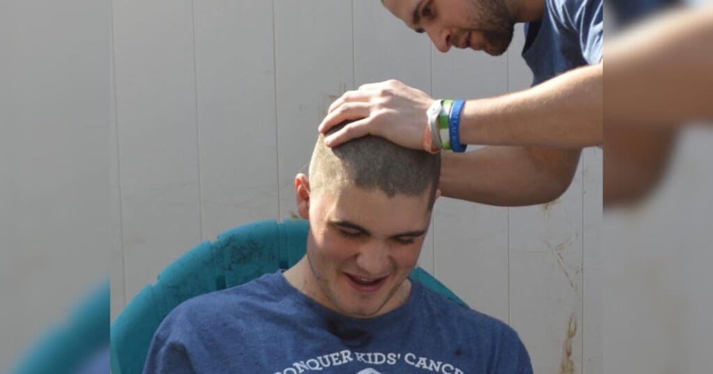 A man is getting his head shaved by another man in a barbershop setting.